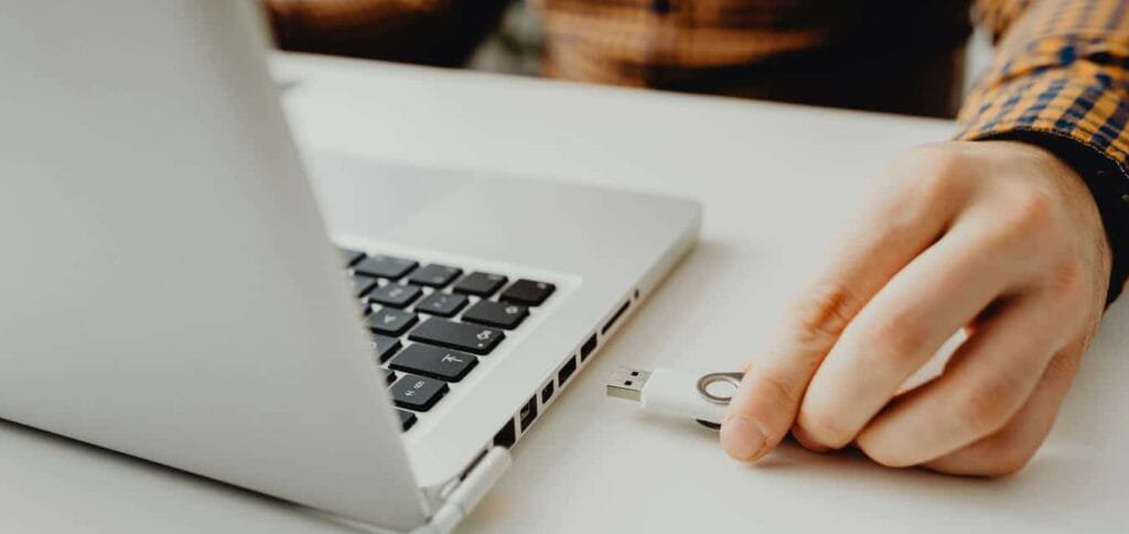Main d'un entrepreneur branchant un périphérique USB sur son ordinateur portable pour illustrer la sécurité du matériel et des logiciels