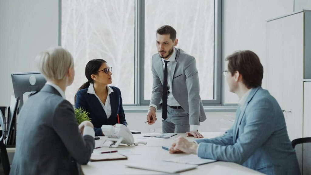 Réunion de comité de direction dans une entreprise, avec un dirigeant présentant un sujet stratégique à son équipe.